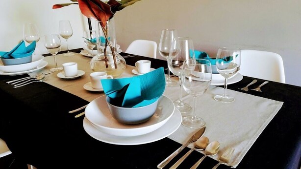 A dining table set with white plates, blue napkins, and a vase with flowers. - TripGeo Apartment Roma (Lisbon)