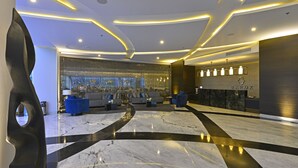 A modern lobby with a marble floor, seating area, and a reception desk.