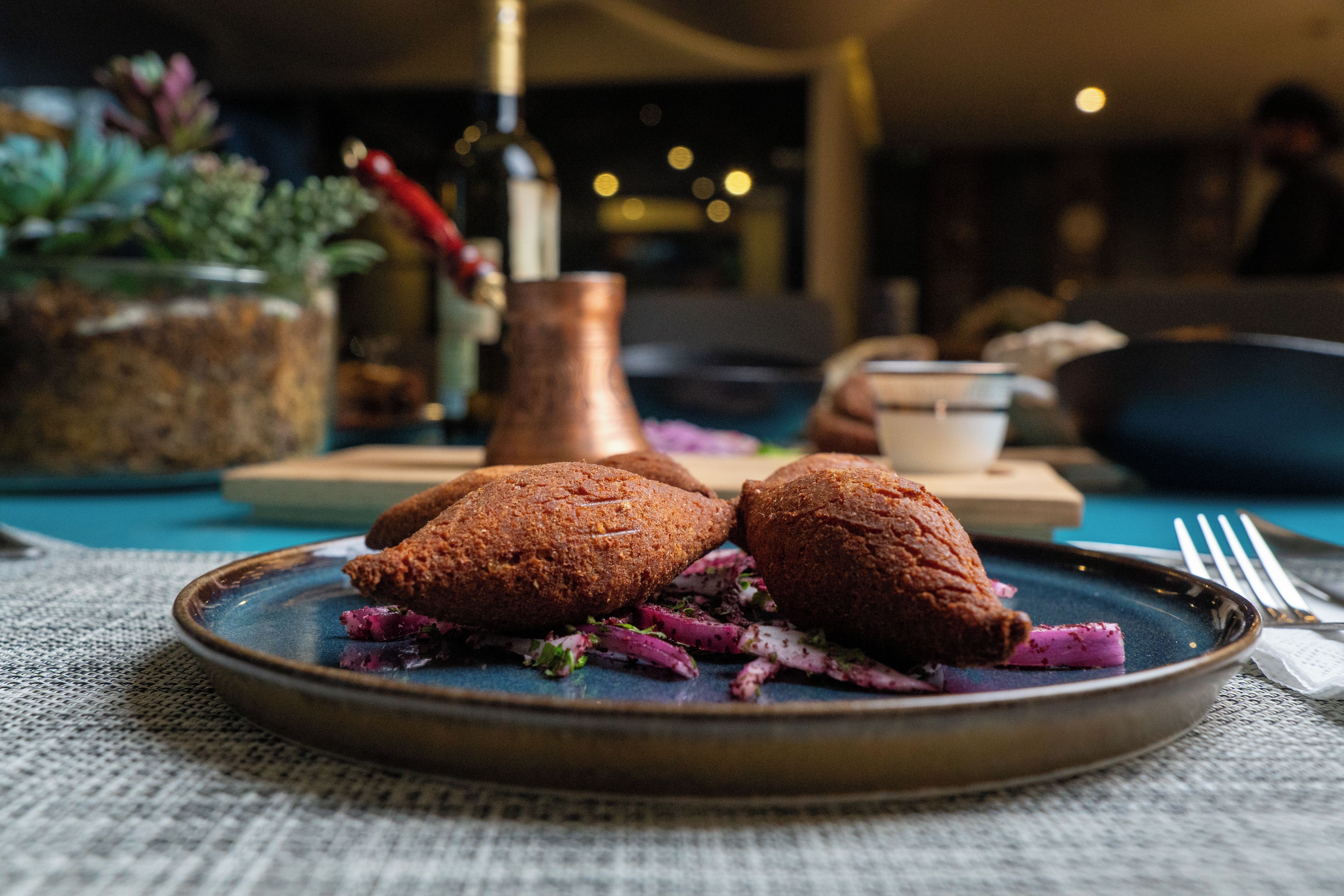 A plate with two round, brown pastries on a blue plate, accompanied by a side of purple and green vegetables.