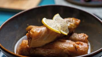 Un tazón con dos rollos de col rellenos, adornados con una rodaja de limón.