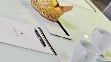 Une table sur laquelle se trouvent un panier de pain, un stylo et deux tasses blanches, le tout posé sur une table en verre.