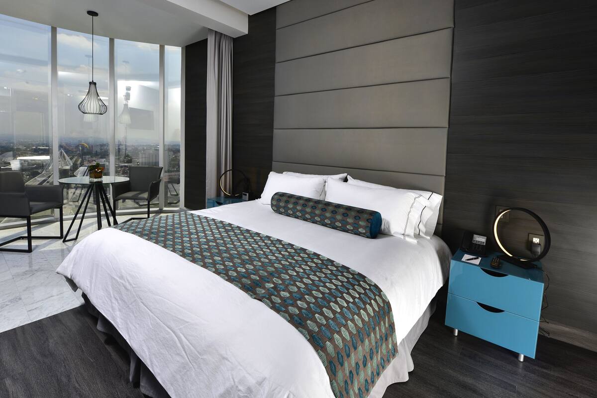 Ein modernes Hotelzimmer mit einem großen Bett, einem Schreibtisch und einem Sessel.