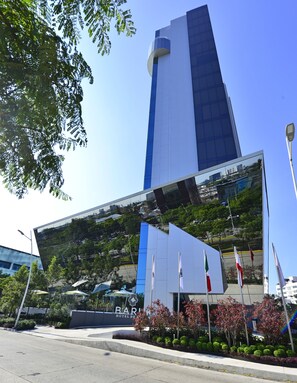 Un hotel moderno con una fachada de vidrio destacada que refleja el paisaje urbano circundante.