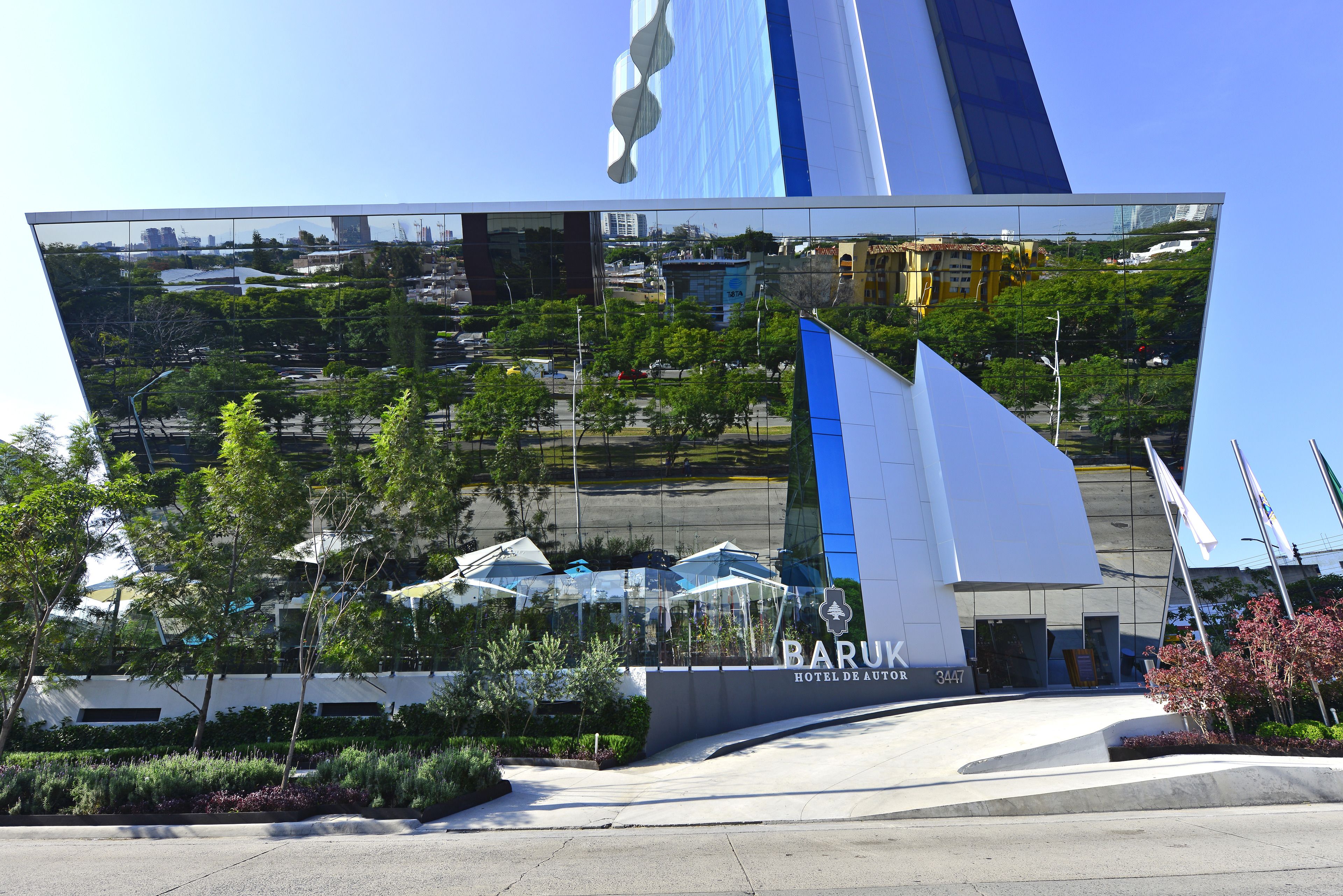 A modern hotel with a unique architectural design, featuring a large reflective facade and a prominent sail-like structure.