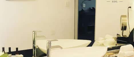 A hotel bathroom with two sinks, a large mirror, and a framed painting on the wall.