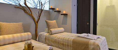 Habitación de hotel con dos camas, una ventana que da a árboles desnudos y una decoración con una rama de madera.