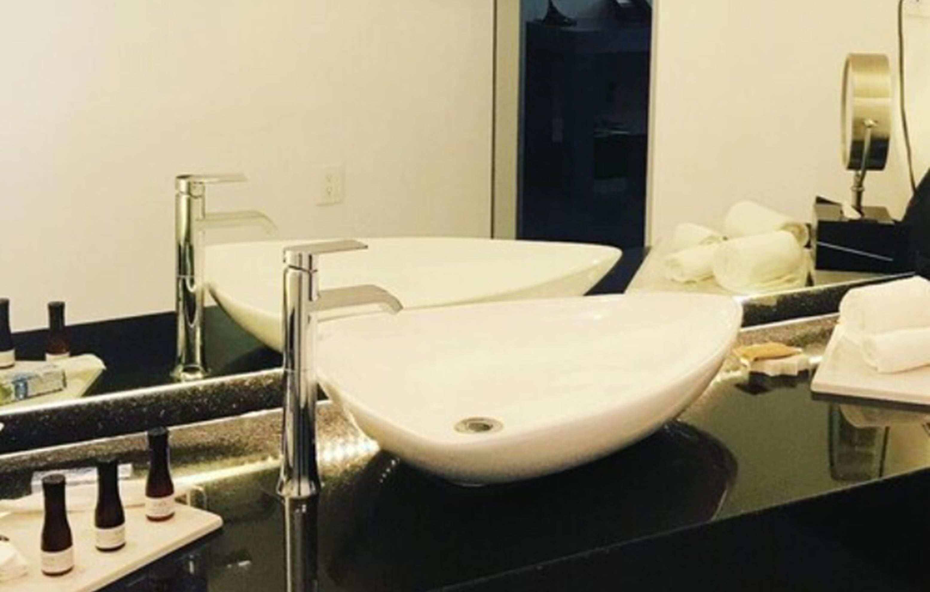 Un baño con un lavamanos blanco, un espejo y una encimera negra.