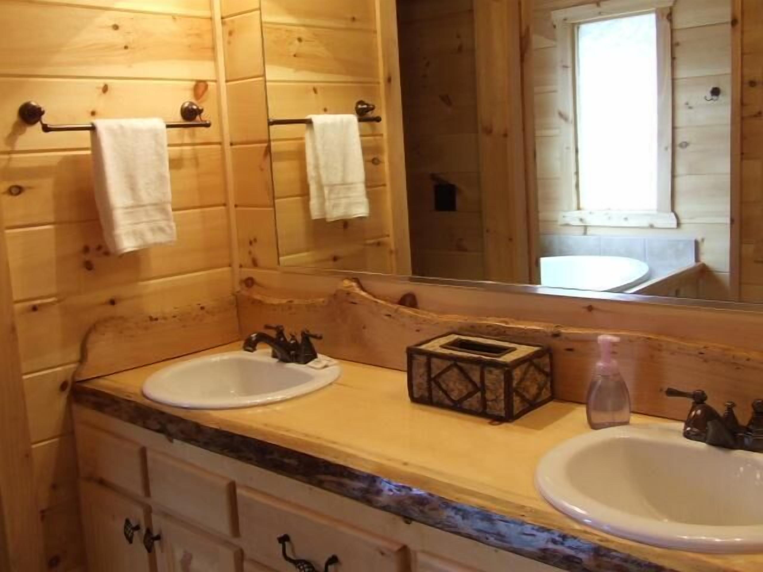 Une salle de bain de style rustique, avec deux lavabos, un miroir et des meubles en bois.