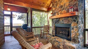 A cozy wooden deck with wicker chairs and a stone fireplace. - Crockett Mountain Lodge Nevaeh Cabin Rentals (Blue Ridge)