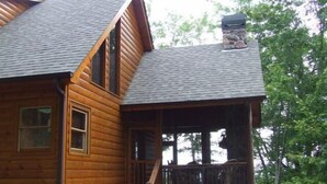A wooden cabin with a stone foundation, a porch, and a chimney. - Crockett Mountain Lodge Nevaeh Cabin Rentals (Blue Ridge)