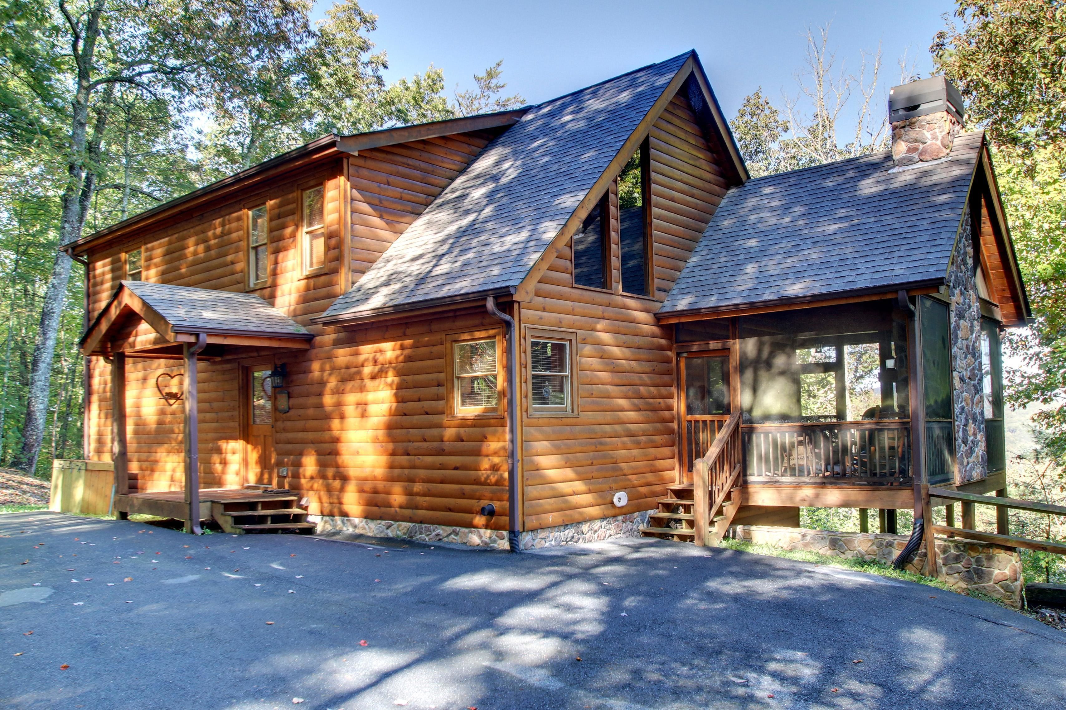A wooden cabin with a stone chimney, a porch, and a deck.