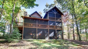 A two-story cabin with a balcony, surrounded by trees. - SERENITY WOODS Apartment 3 NEVAEH CABIN RENTALS (Mineral Bluff)