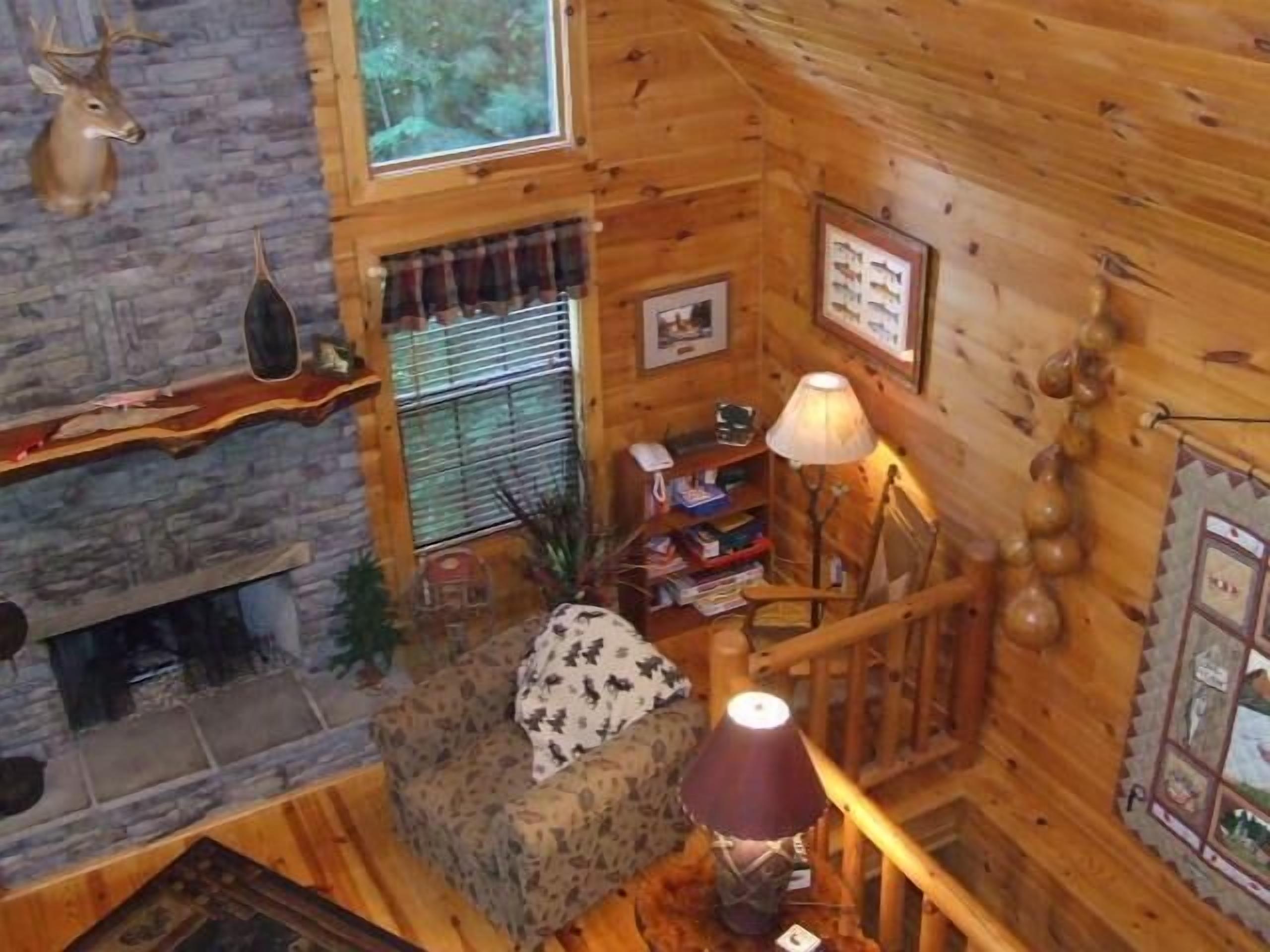 L’intérieur d’un chalet chaleureux, avec une cheminée en pierre, des murs en bois, un canapé moelleux et une lampe.