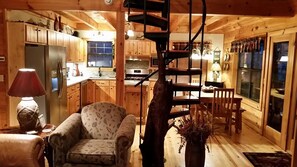 Ein gemütliches Blockhaus-Interieur mit Essbereich, Küche und einer Wendeltreppe.