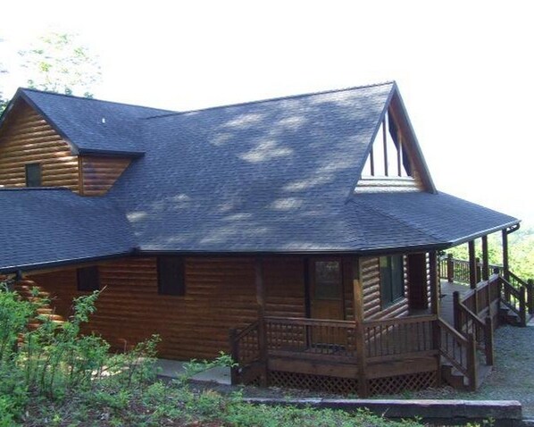 A wooden cabin with a porch and a steeply pitched roof.