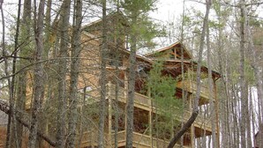 A multi-story log cabin surrounded by trees.