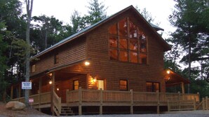 A log cabin with a porch, large windows, and a sign for Wolf Creek Builders.