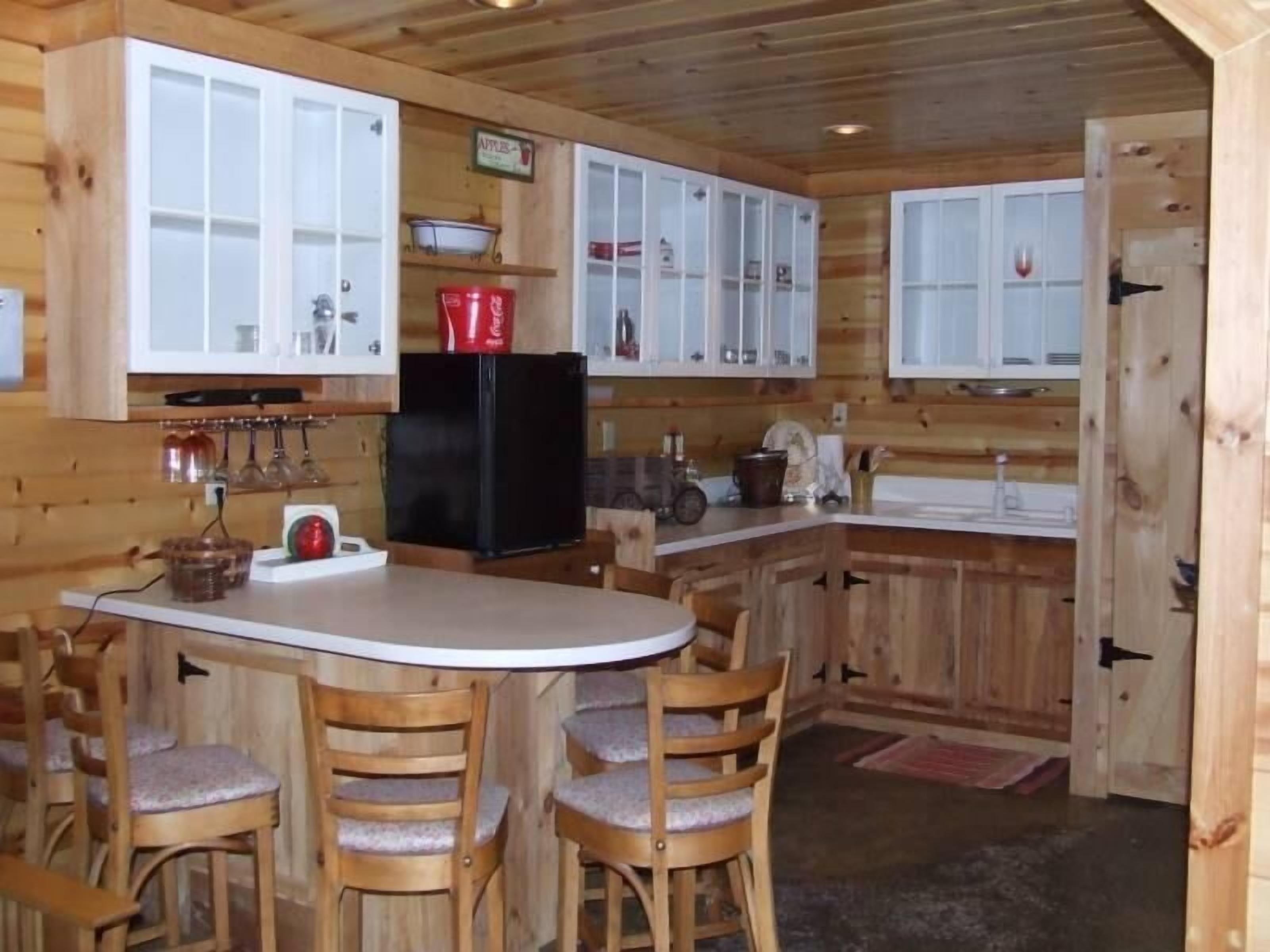 A wooden cabin kitchen with a central island, wooden chairs, and white cabinets.