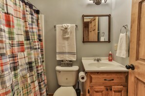 A bathroom with a toilet, sink, wooden cabinet, and a mirror. - CAMP RISING FISH-NEVAEH CABIN RENTALS (Mineral Bluff)