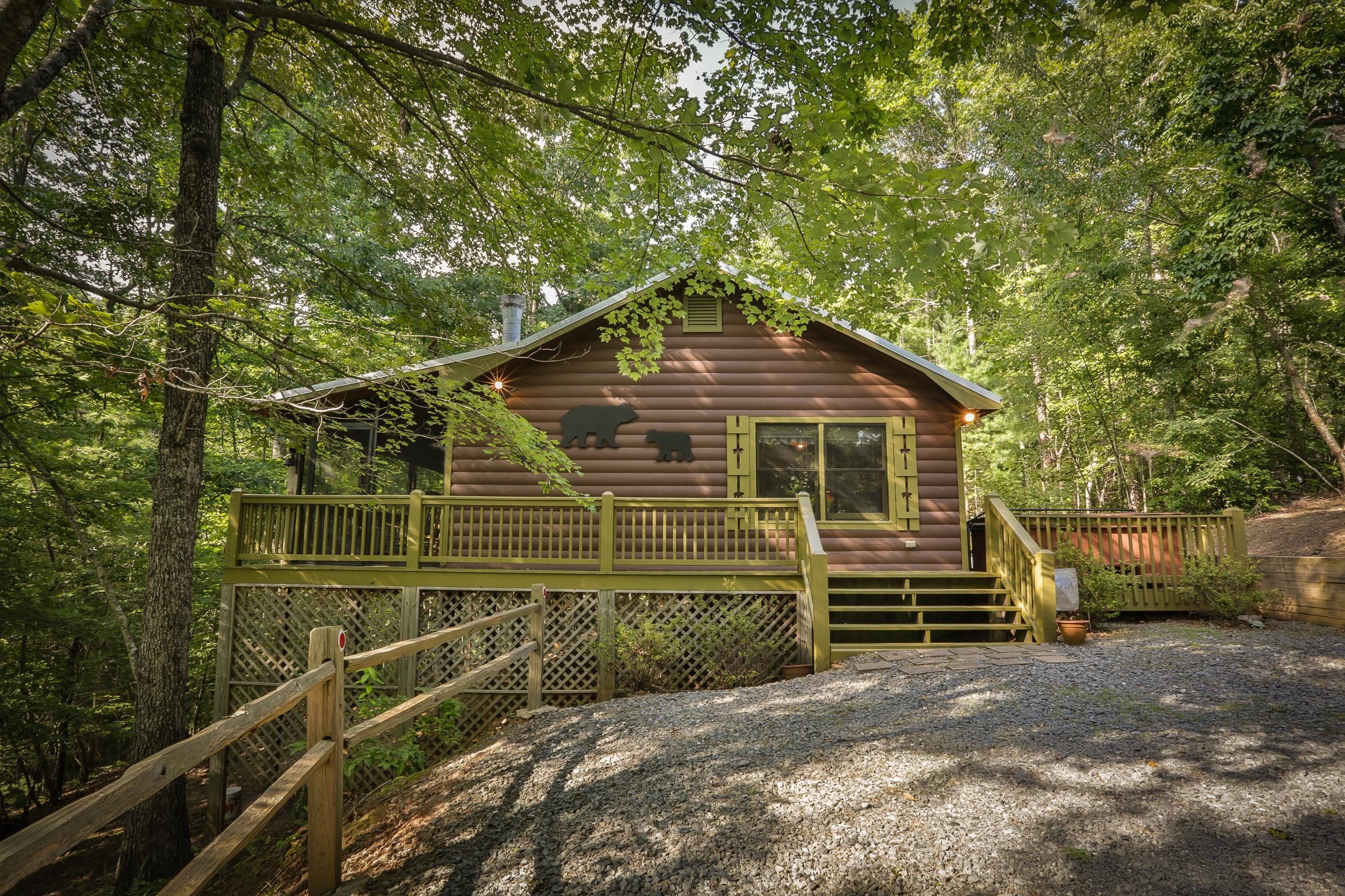 A rustic cabin with a wooden deck and a staircase leading to the entrance.