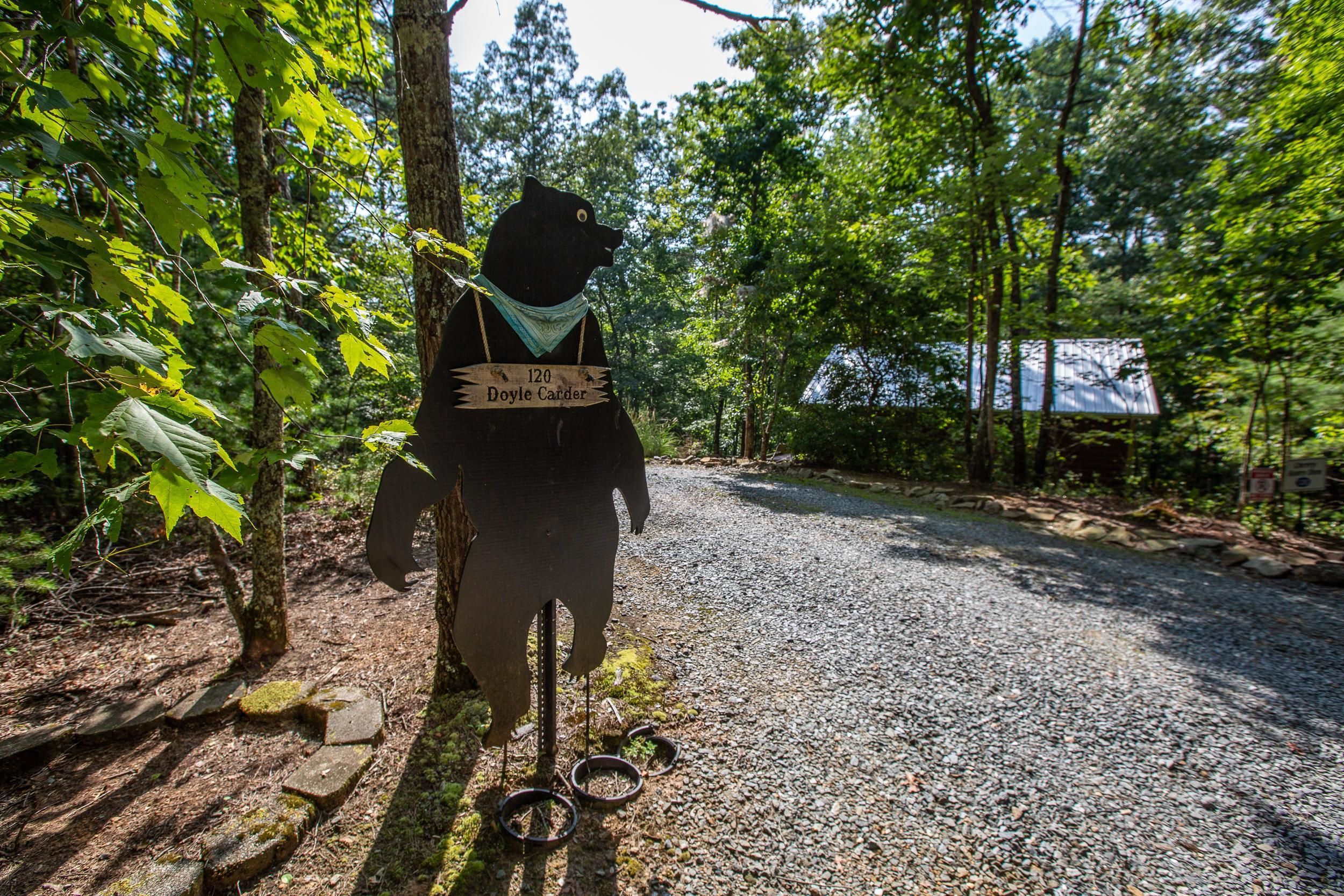 A person walking on a gravel path in a wooded area with a sign reading "120 Doyle Carder".