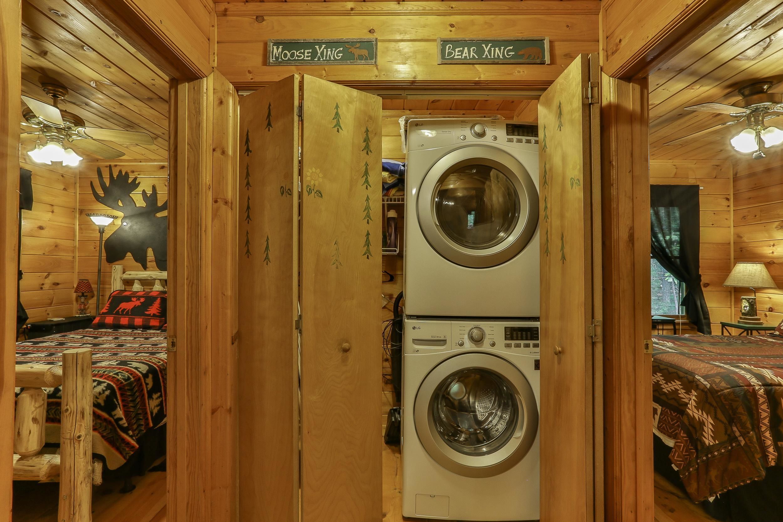 A cabin interior with a bed, a washing machine, and a ceiling fan.