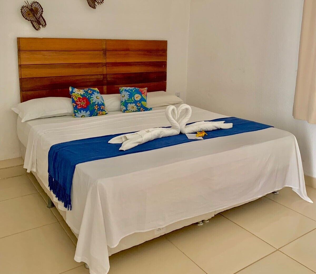 A neatly made bed with a blue throw blanket and a white towel arranged in a swan shape.