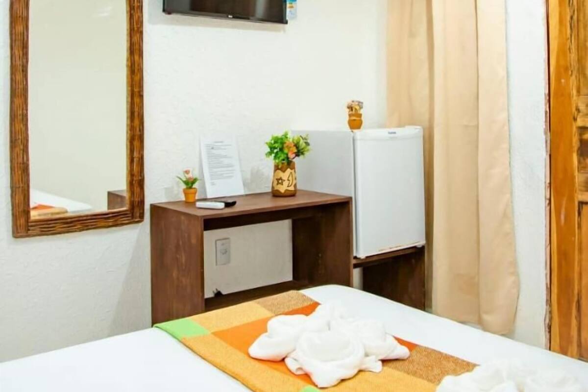 Ein Hotelzimmer mit einem Bett, einem Schreibtisch mit Computer, einem Fernseher und einer Klimaanlage.