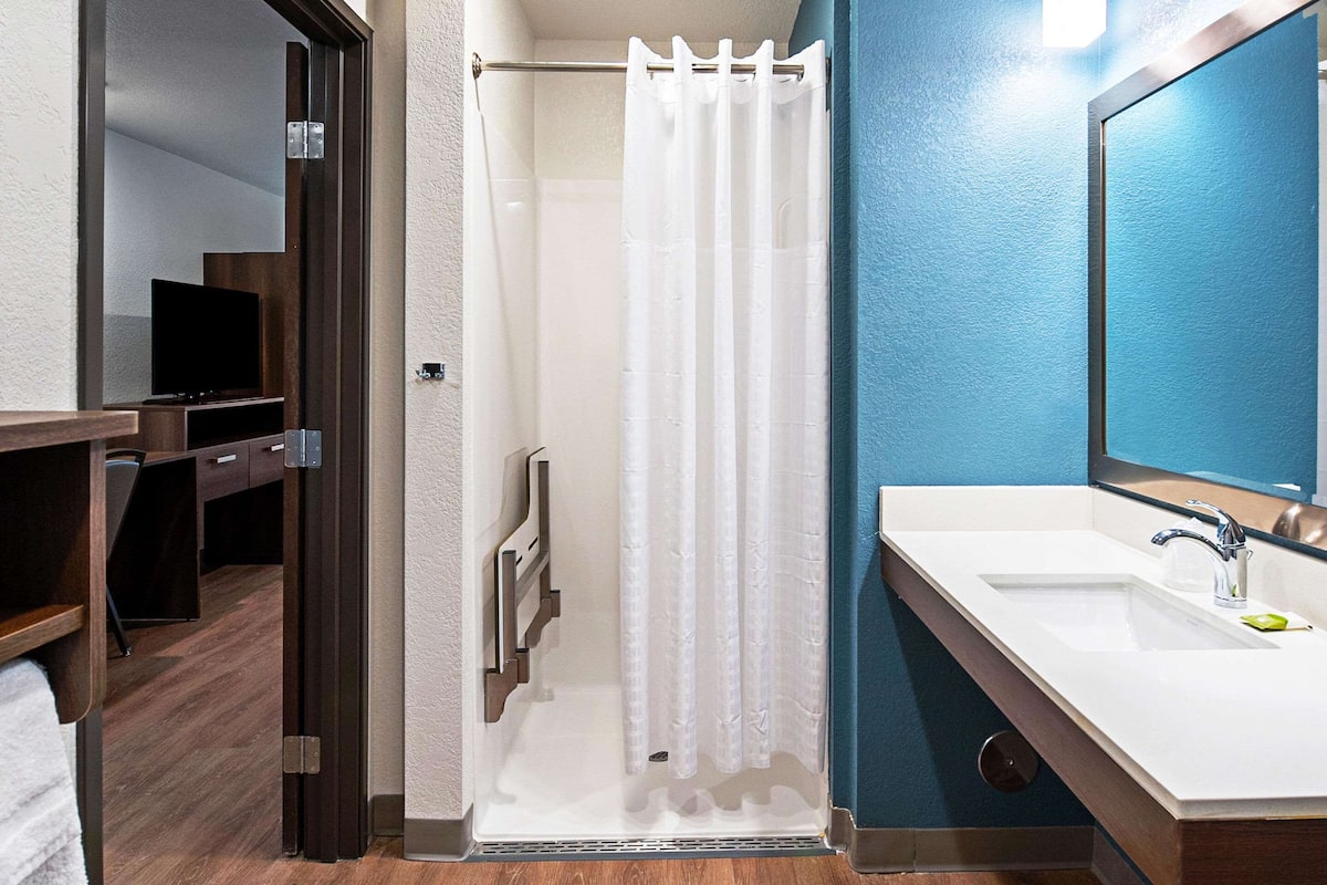 A modern bathroom with a shower, a sink, and a mirror.