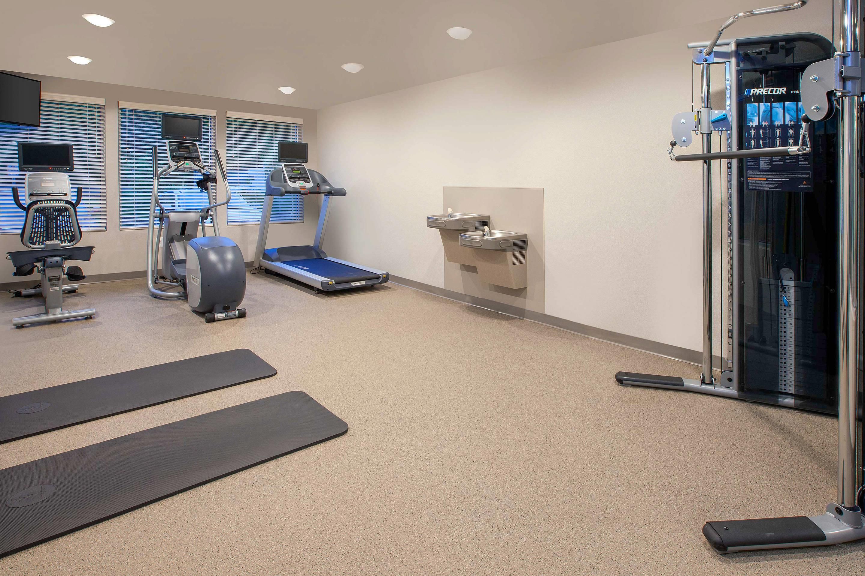 A gym with exercise equipment, a treadmill, and a water station.