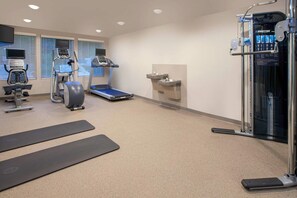 Une salle de sport équipée de matériel d’exercice, d’un tapis de course et d’un point d’eau.