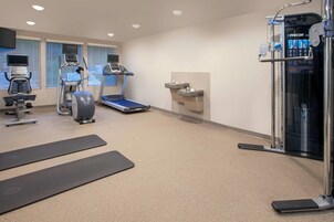 Un gimnasio con equipamiento de ejercicio, cinta de correr y estación de hidratación.
