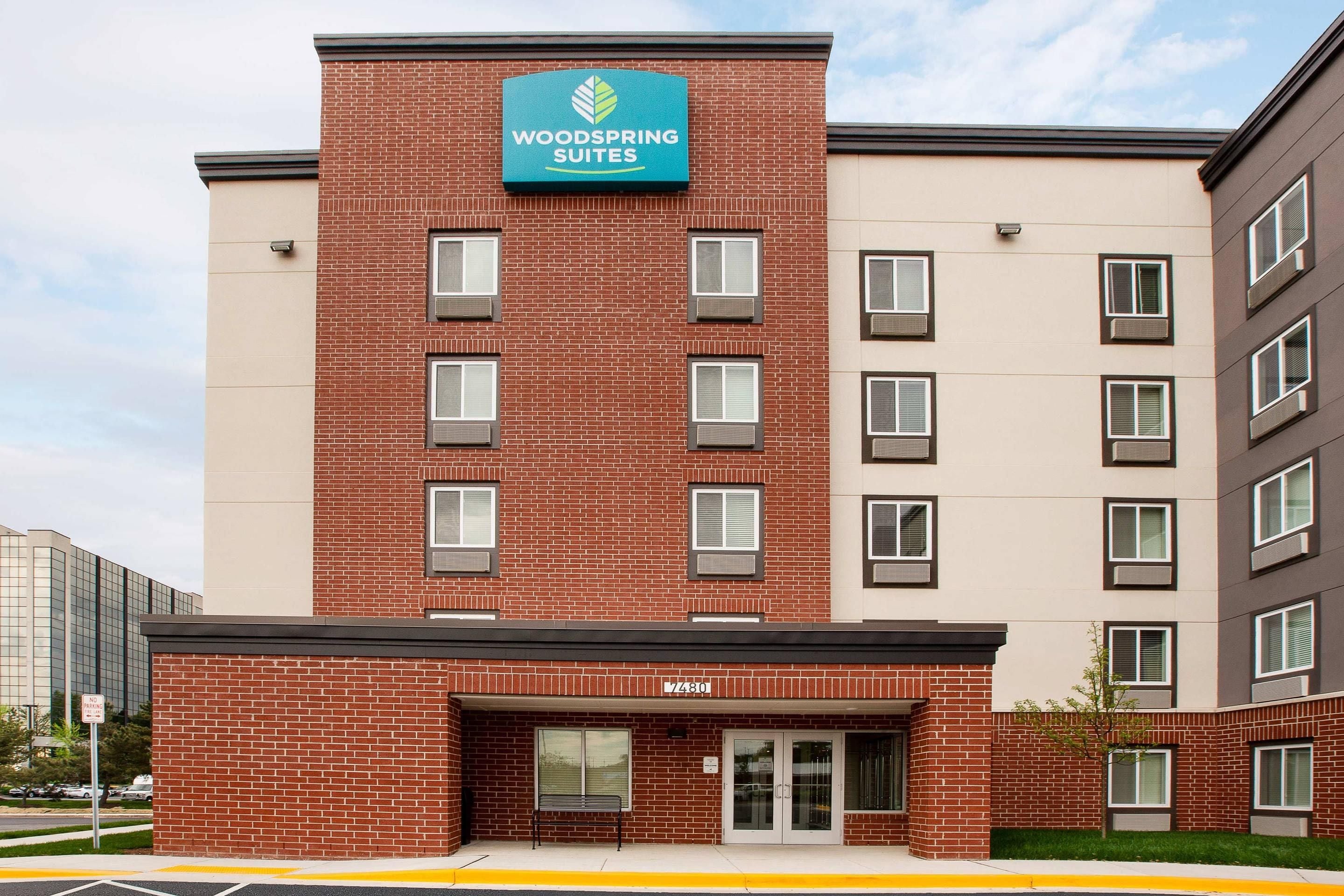 Ein mehrstöckiges Hotelgebäude mit einer auffälligen Schrifttafel für 'Woodspring Suites' an der Fassade.