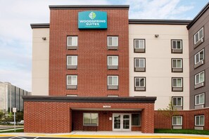 A multi-story hotel building with a prominent sign for 'Woodspring Suites' on the facade. - WoodSpring Suites Washington DC Northeast Greenbelt (Greenbelt)