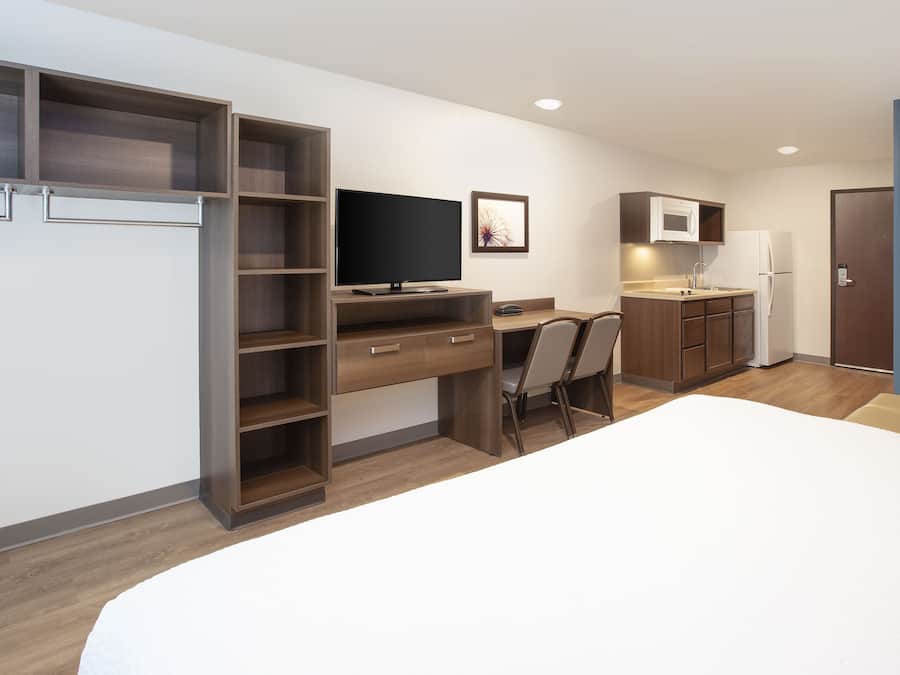 Een moderne, compacte hotelkamer met een bed, een bureau, een televisie, een magnetron en een koelkast.