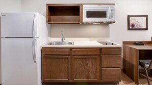 Una cocina compacta con un refrigerador blanco, un microondas, un lavamanos y armarios de madera.