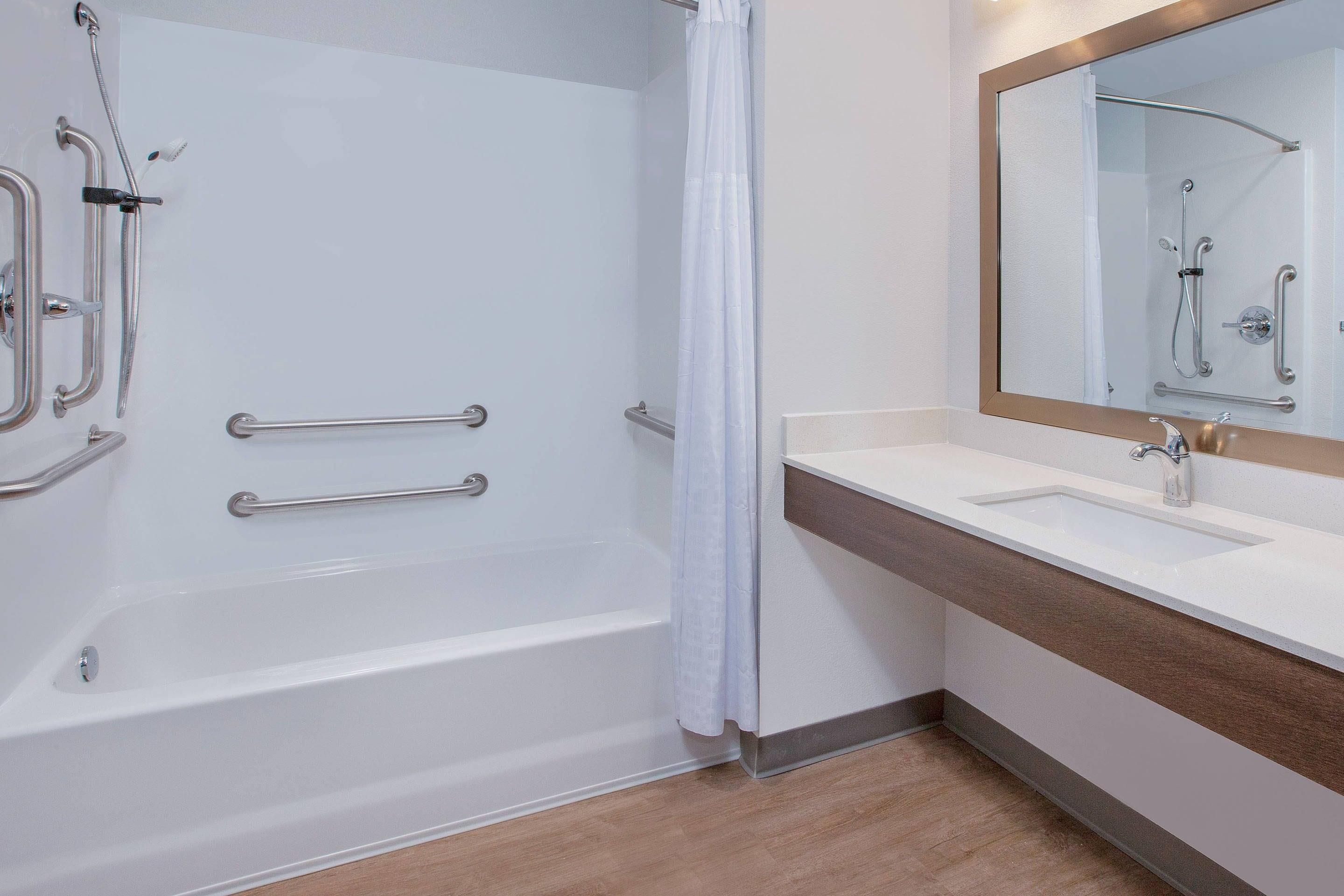 A modern bathroom with a bathtub, shower, and vanity.