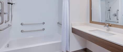 A modern bathroom with a bathtub, shower, and vanity.
