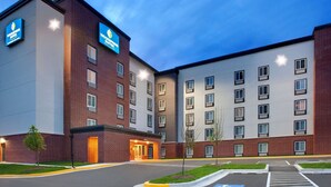 Un hotel de varios pisos con fachada de ladrillo, techo plano y estacionamiento con espacios para discapacitados.