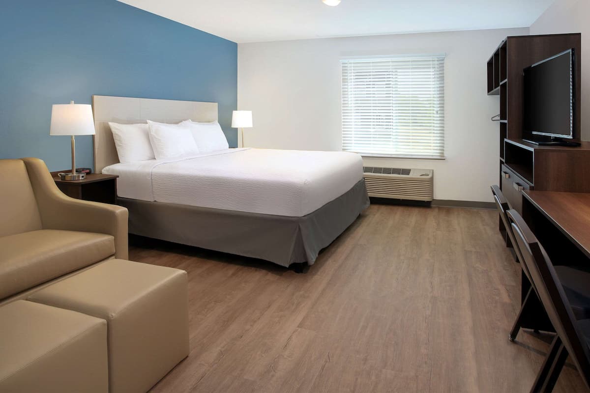 Een hotelkamer met een bed, een televisie, een bureau en een stoel.