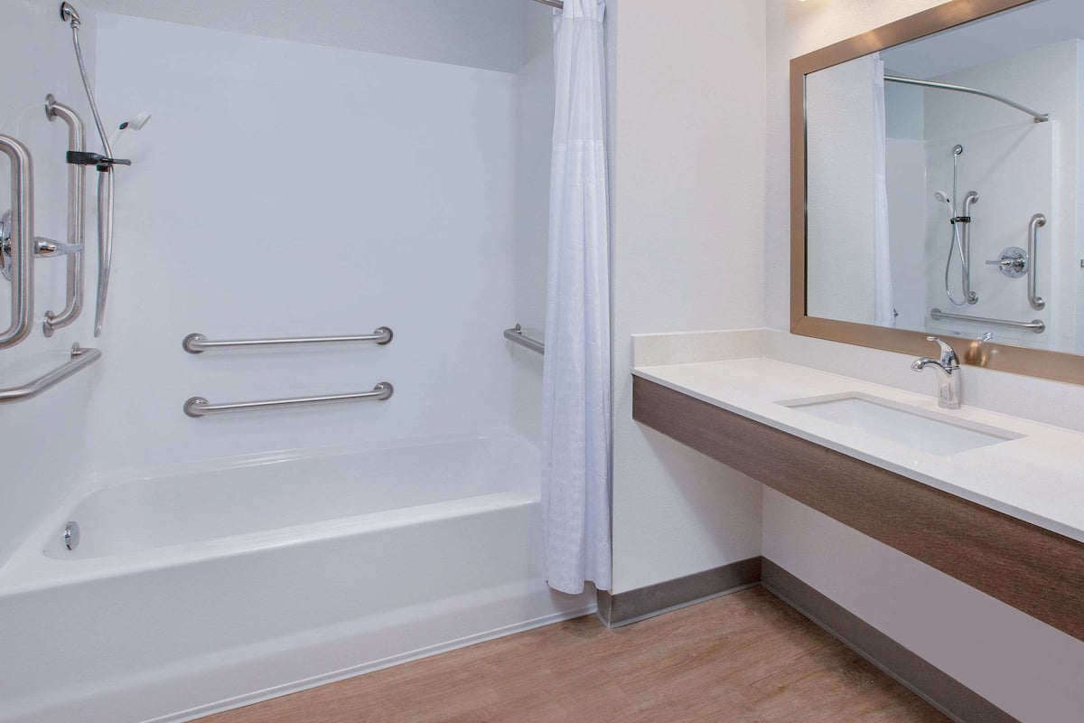 Een moderne badkamer met bad, douche en wastafel.