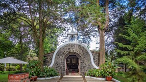 A stone archway leading to a building with a bell tower, surrounded by lush greenery and potted plants. - Hyatt Centric San Salvador (Antiguo Cuscatlán)