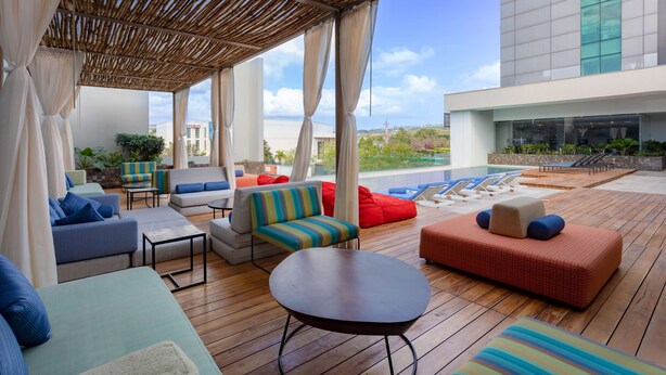 A rooftop lounge area with various seating options, including sofas and chairs, and a poolside view. - Hyatt Centric San Salvador (Antiguo Cuscatlán)
