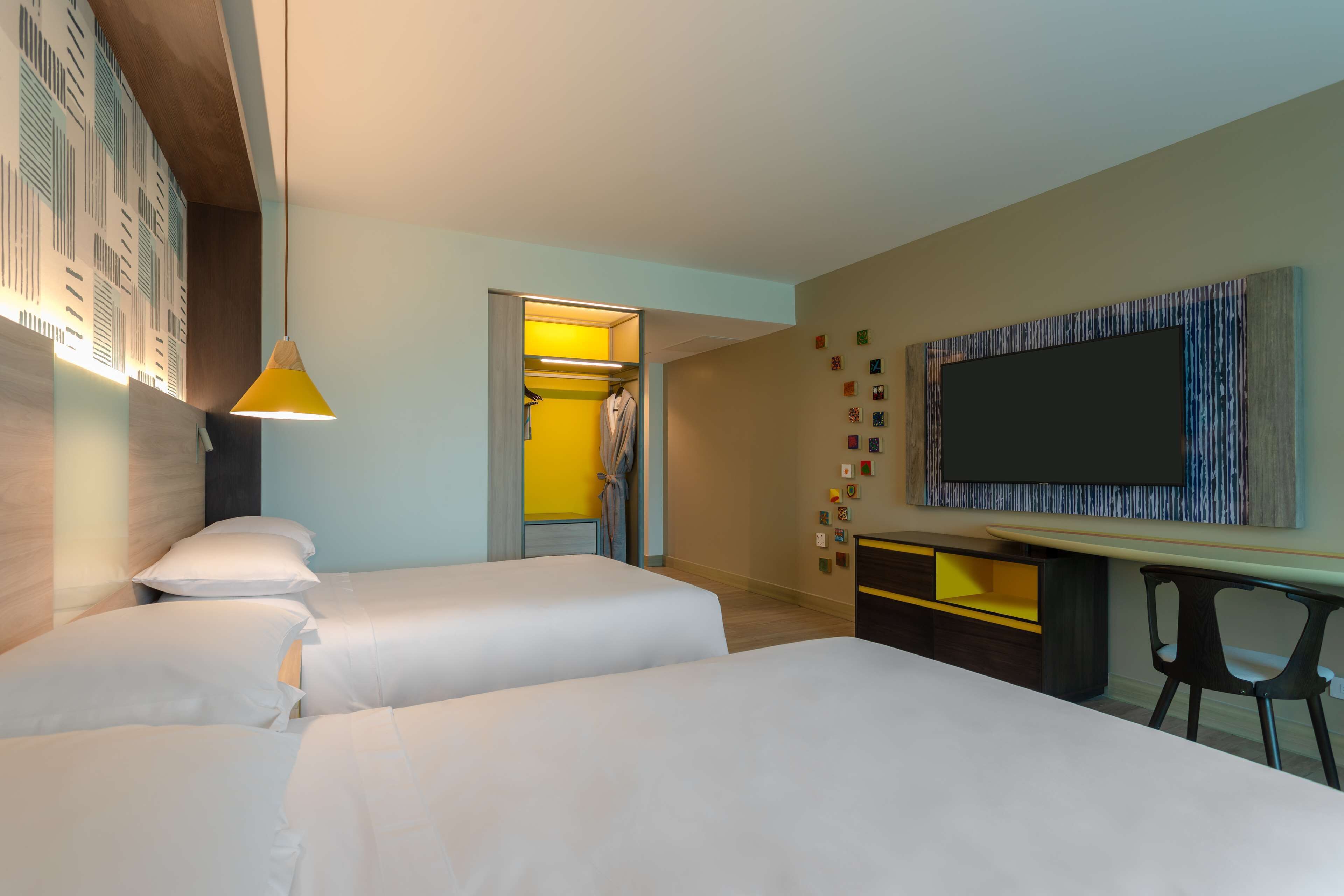 Une chambre d’hôtel avec deux lits, un bureau, une télévision et une armoire.