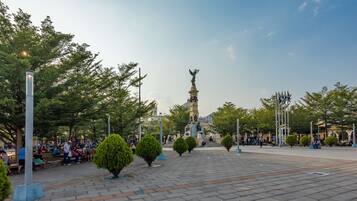 Une place publique avec un monument central, des bancs et des arbres.