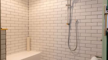 Un baño con paredes de ladrillo blanco, suelo de diseño geométrico, un cabezal de ducha y una bañera.