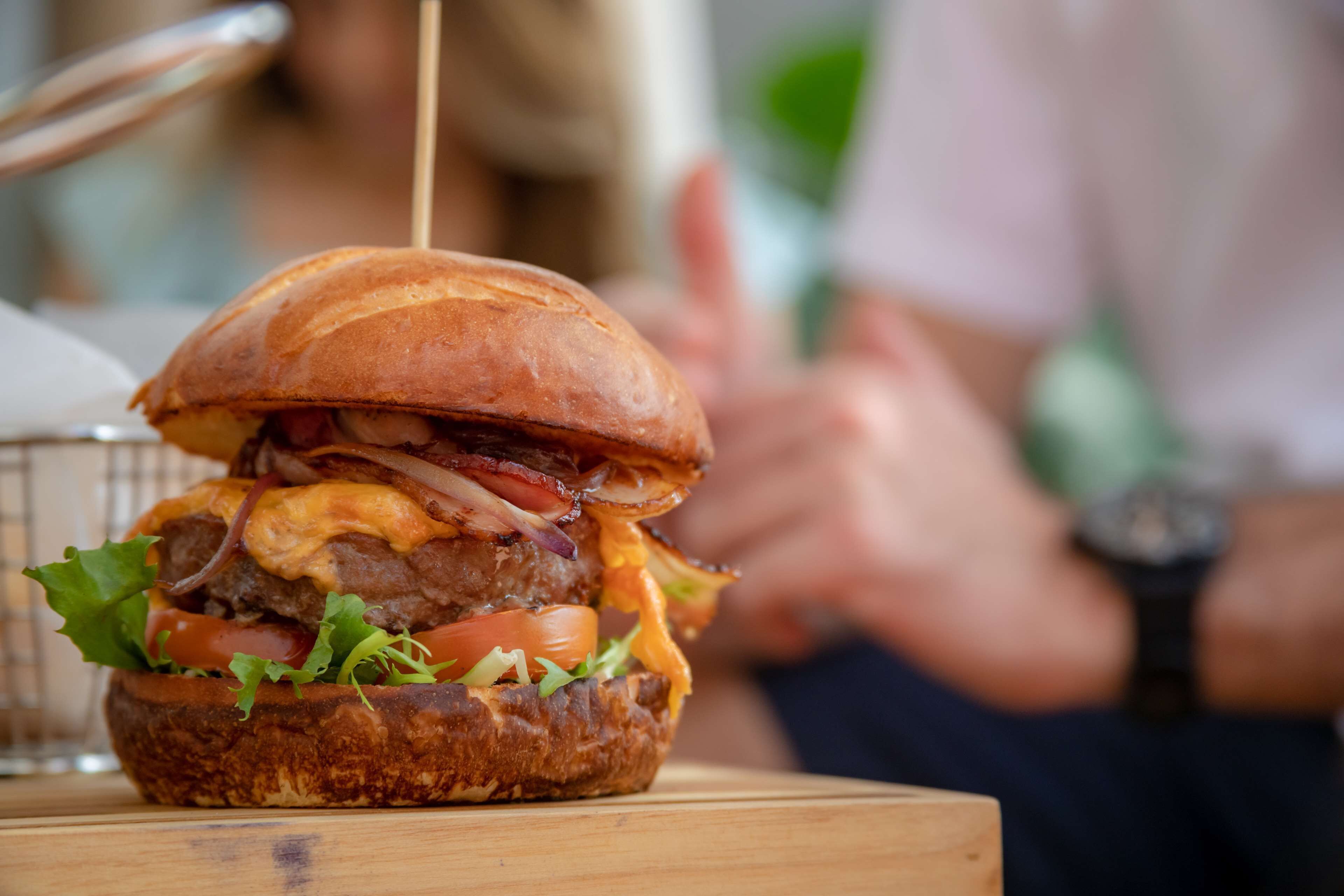 A close-up of a burger with visible ingredients like lettuce, tomato, and cheese.