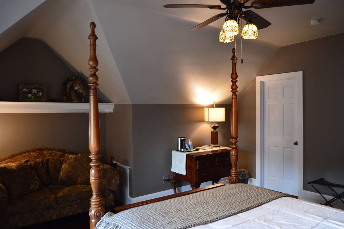 A bedroom with a four-poster bed, a ceiling fan, a nightstand, and a dresser.