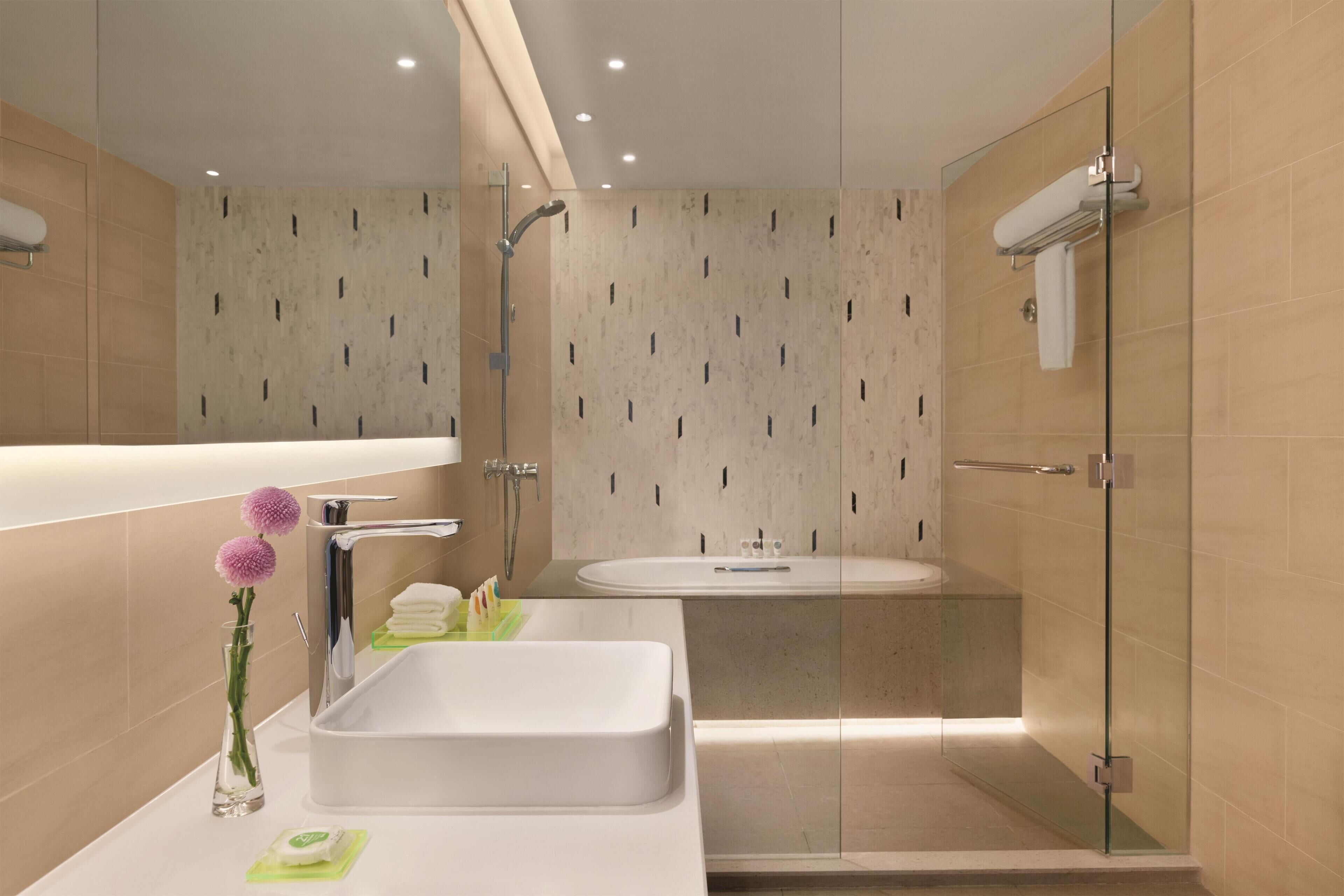 A modern bathroom with a glass-enclosed shower, a large sink, and a mirror.