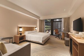 A hotel room with a bed, a desk, a chair, a TV, and a view of the city. - Hyatt Place Chengdu Pebble Walk (Chengdu)